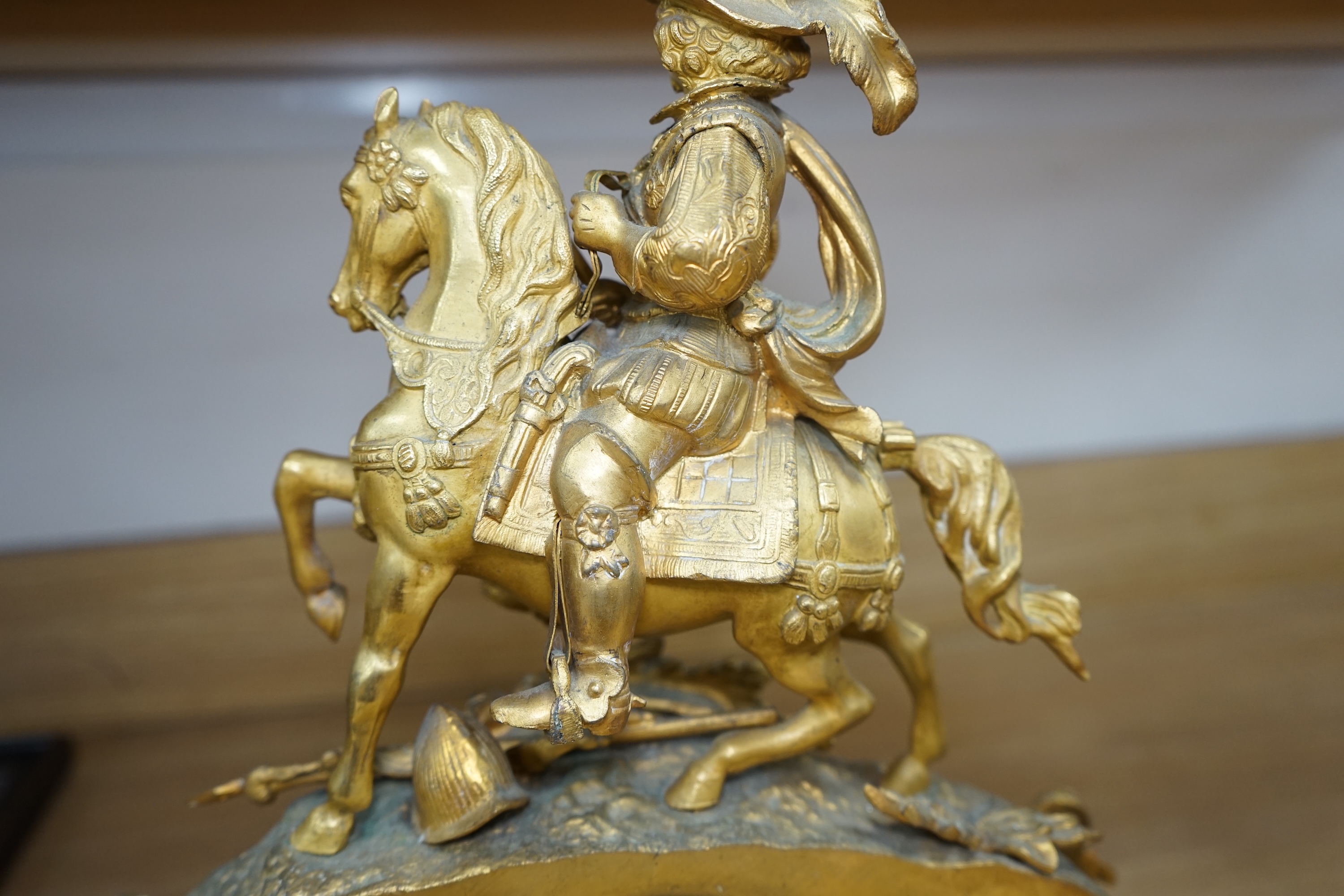 A late 19th century French ormolu mantel clock surmounted with a cavalier on horseback, key and pendulum, 38cm. Condition - fair to good